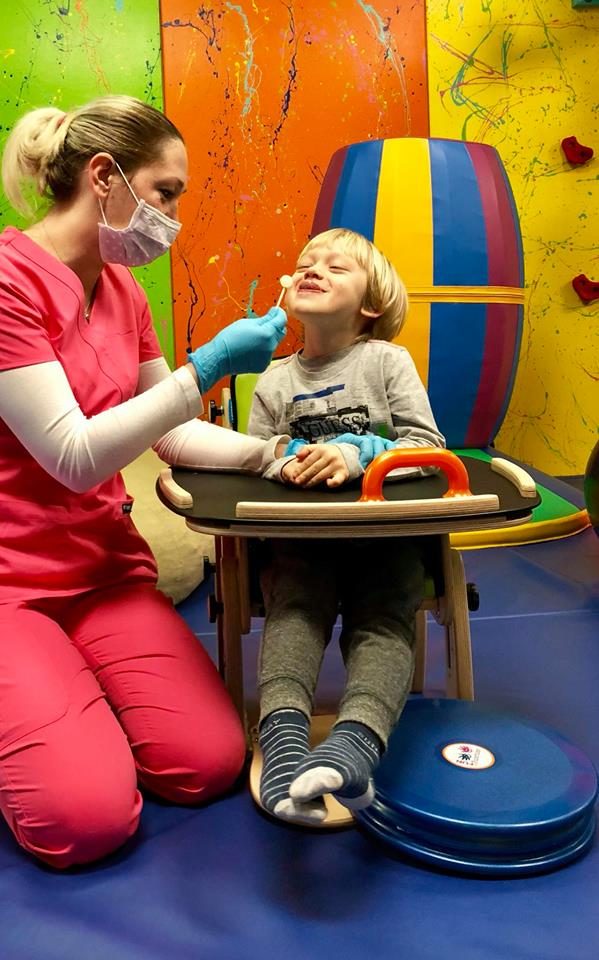 A TOTville therapist gently working with a smiling child during a feeding therapy session.
