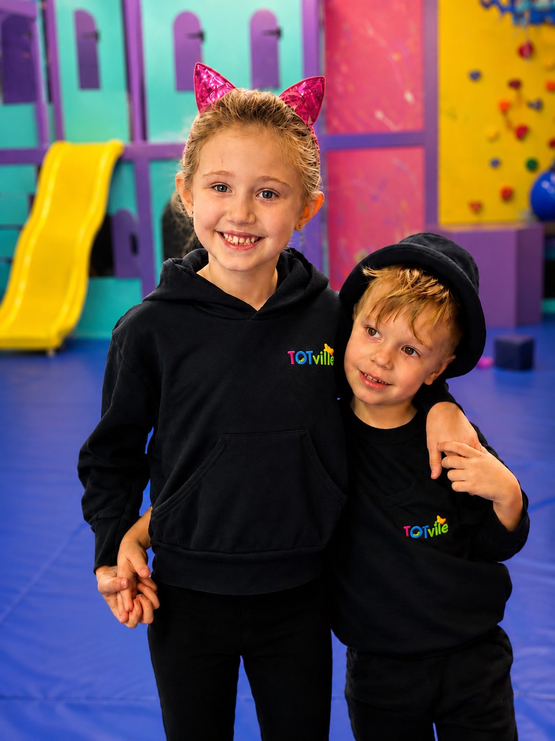 Two children wearing TOTville hoodies in the sensory gym.