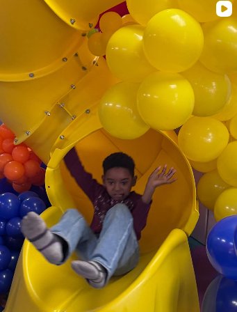 A child going down the yellow tube slide at TOTville.